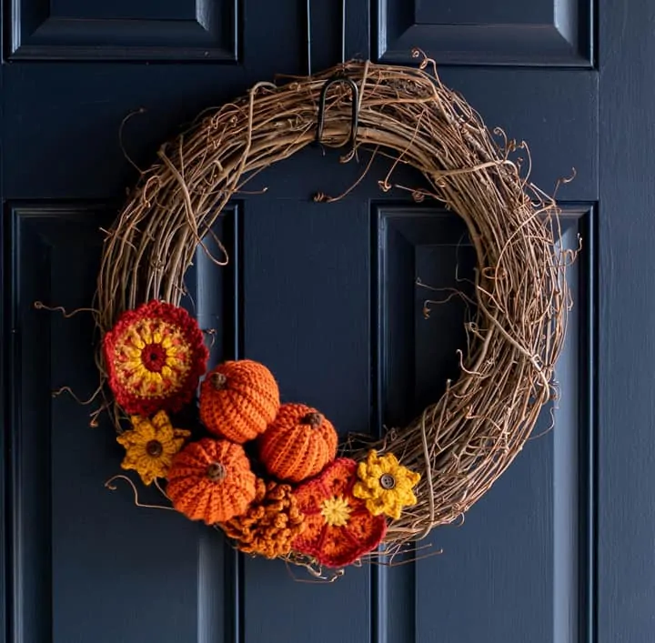 Grapevine wreath with crochet pumpkins and flowers on a blue door