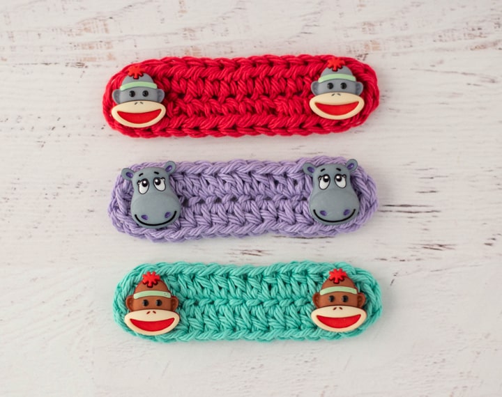 Red, Purple and Green crochet ear savers with monkey and hippo buttons