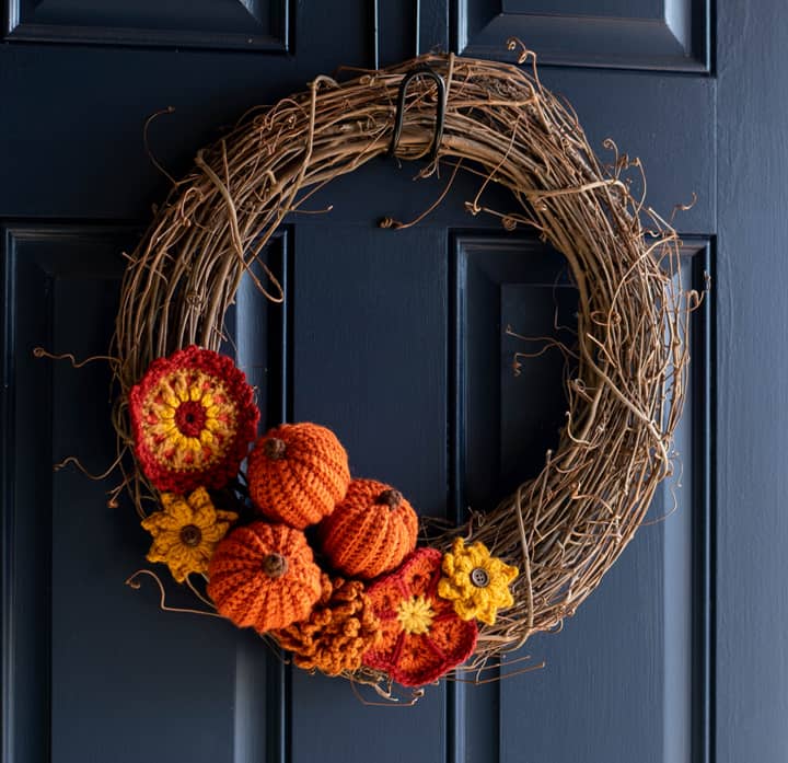 Grapevine wreath with crochet pumpkins and flowers on a blue door