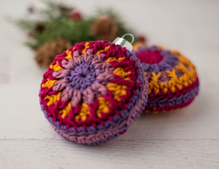 crochet ornaments in jewel tone purple, pink and gold yarn.