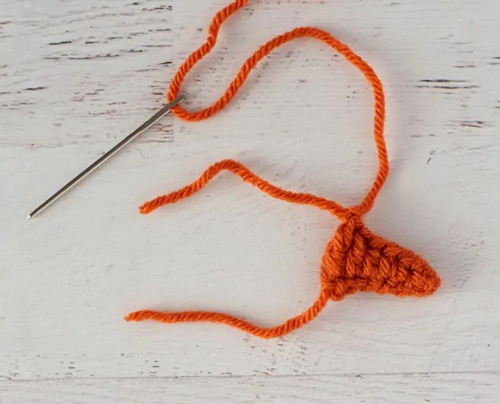 Orange crochet triangle nose with yarn needle