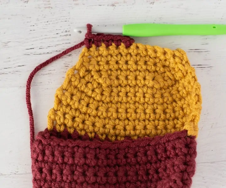 burgundy and yellow crochet stocking heel in progress with green crochet hook