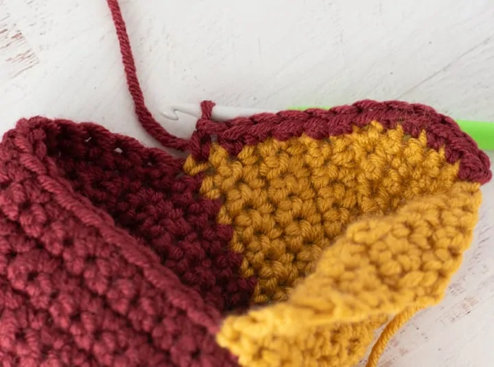 burgundy and yellow crochet stocking heel in progress with green crochet hook