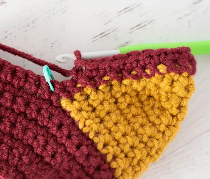 burgundy and yellow crochet stocking heel in progress with green crochet hook