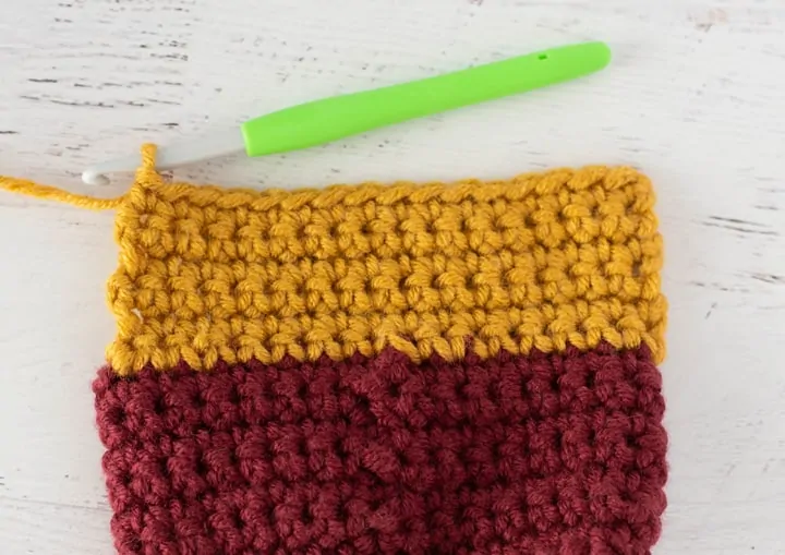 burgundy and yellow crochet stocking heel in progress with green crochet hook