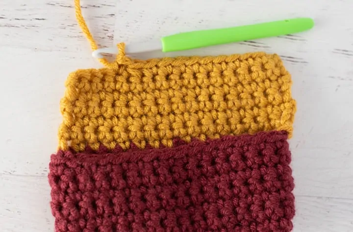 burgundy and yellow crochet stocking heel in progress with green crochet hook