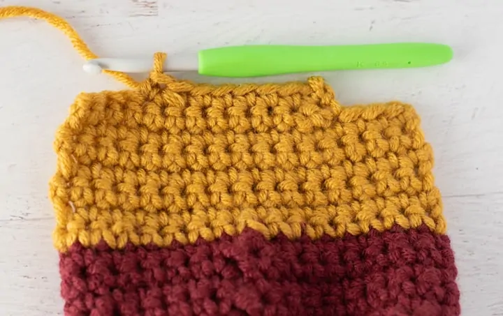 burgundy and yellow crochet stocking heel in progress with green crochet hook