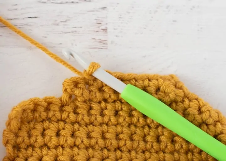 burgundy and yellow crochet stocking heel in progress with green crochet hook