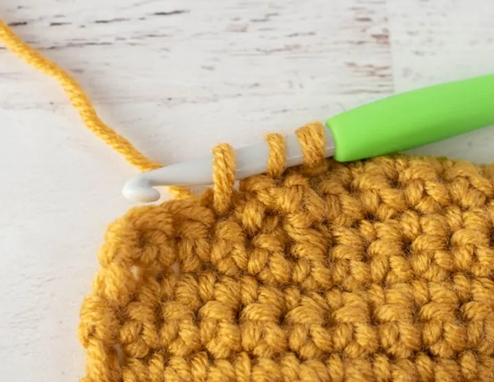 burgundy and yellow crochet stocking heel in progress with green crochet hook