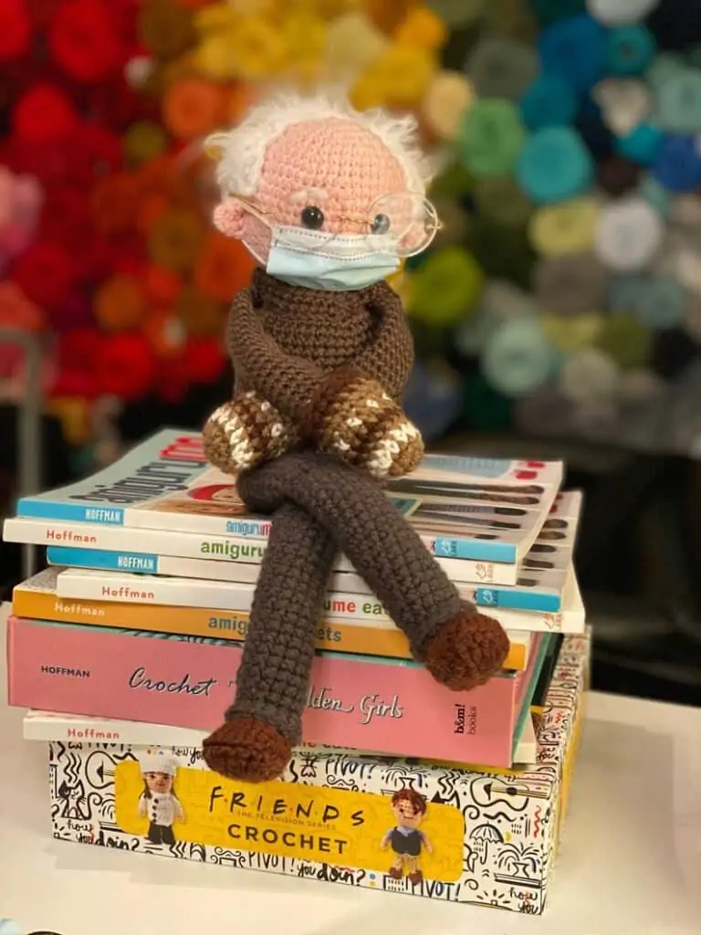 Crochet doll with glasses, white hair, mask and colorful mittens