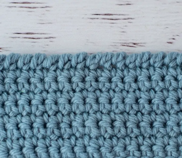 blue crochet piece and wood crochet hook, demonstrating reverse single crochet stitch