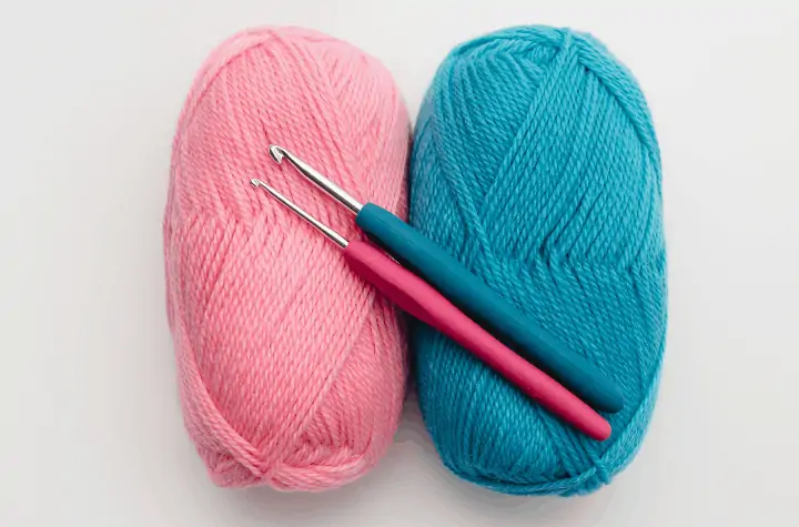 pink and blue yarn and crochet hooks