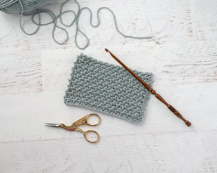 gray crochet sample with stork scissors and wood hook