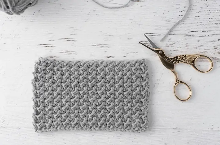 crochet stitch sample in gray yarn with stork scissors