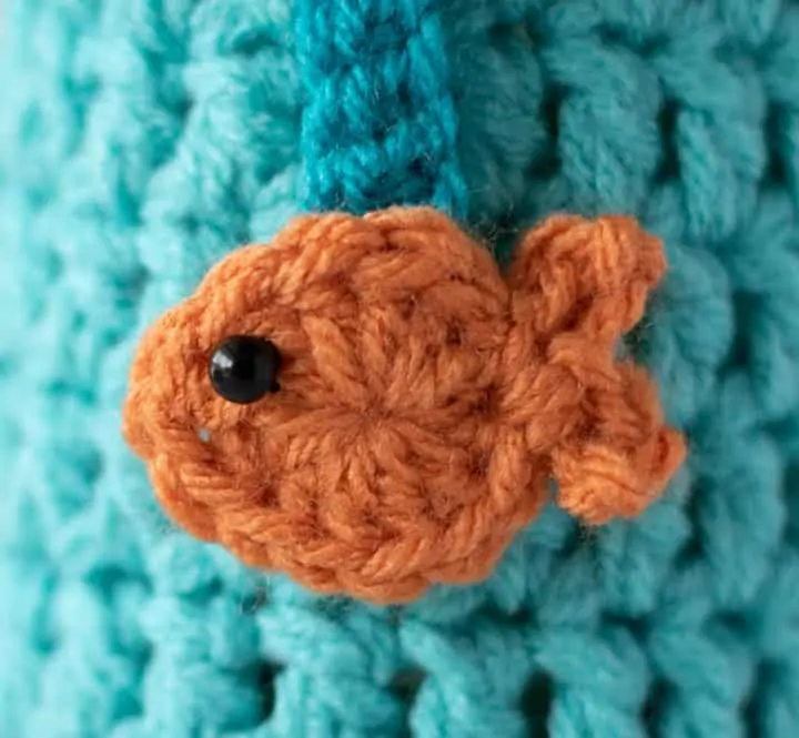 close up of orange crochet fish on blue crochet background