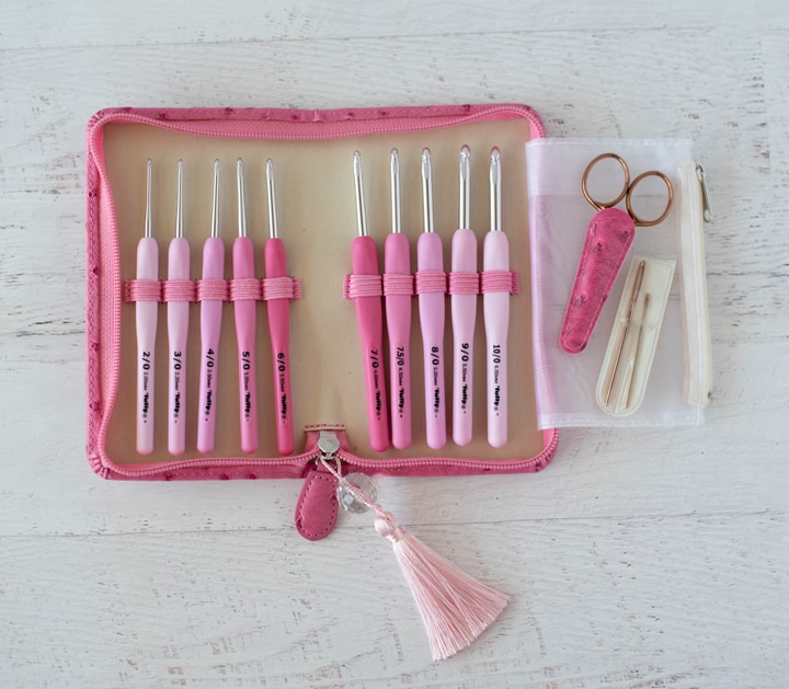 Pink crochet hooks in case with scissors and tapestry needles