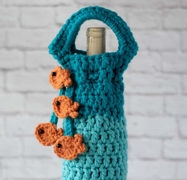 Top of blue crochet wine cozy with orange fish on tie