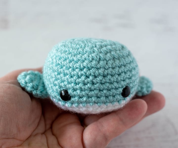 blue and white crochet whale on hand