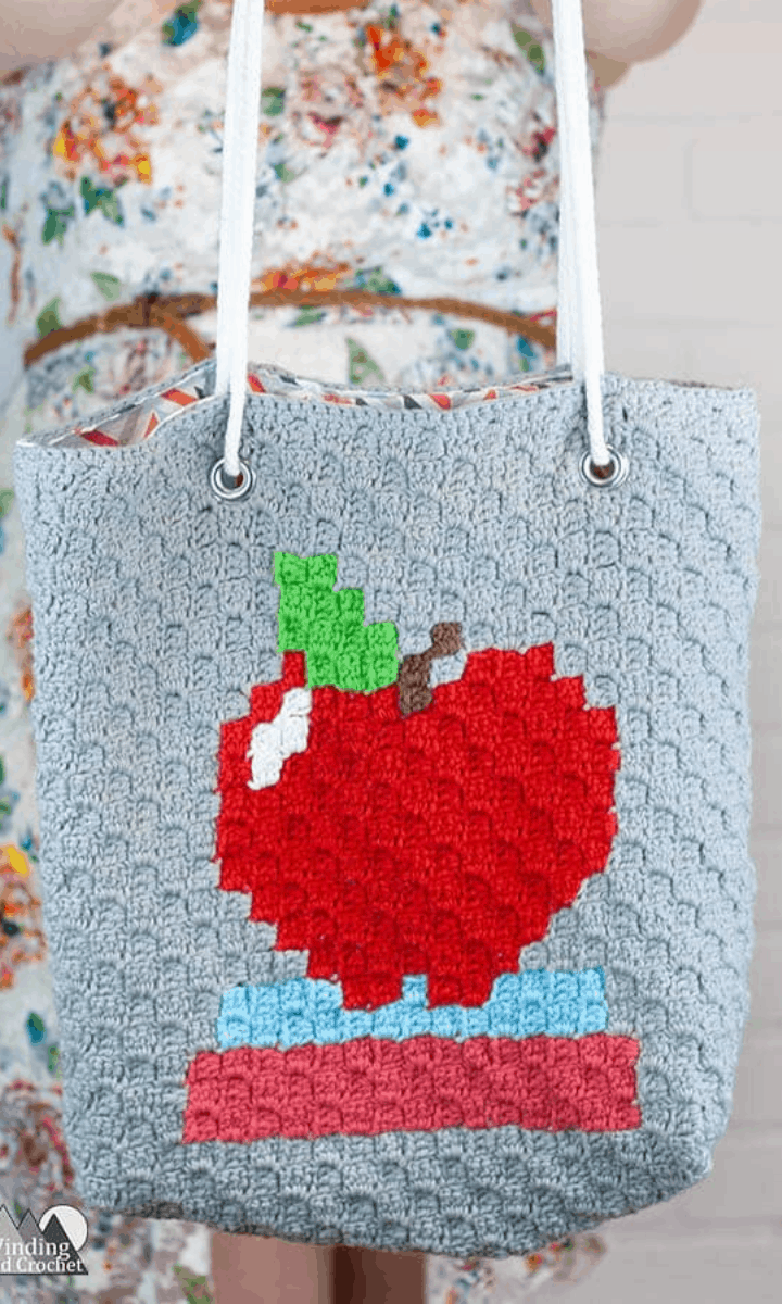 crochet corner-to-corner bag with apple and books on it