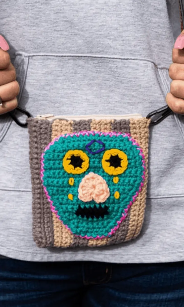 person holding a colorful crochet skull bag