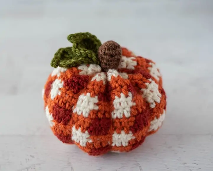 crochet orange plaid pumpkin with brown steam and green leaves