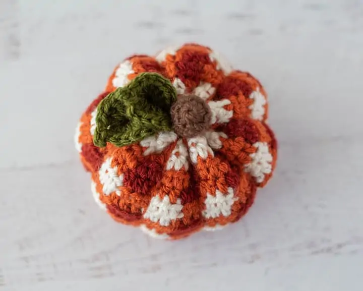 top of orange crochet plaid pumpkin with green leaves and brown stem