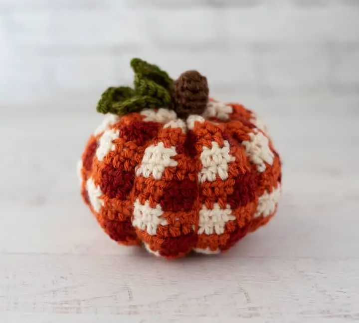 crochet orange plaid pumpkin with brown steam and green leaves