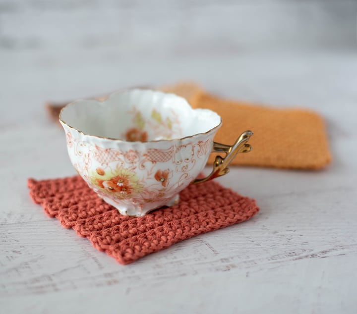 Coffee cup on rust color crochet coaster