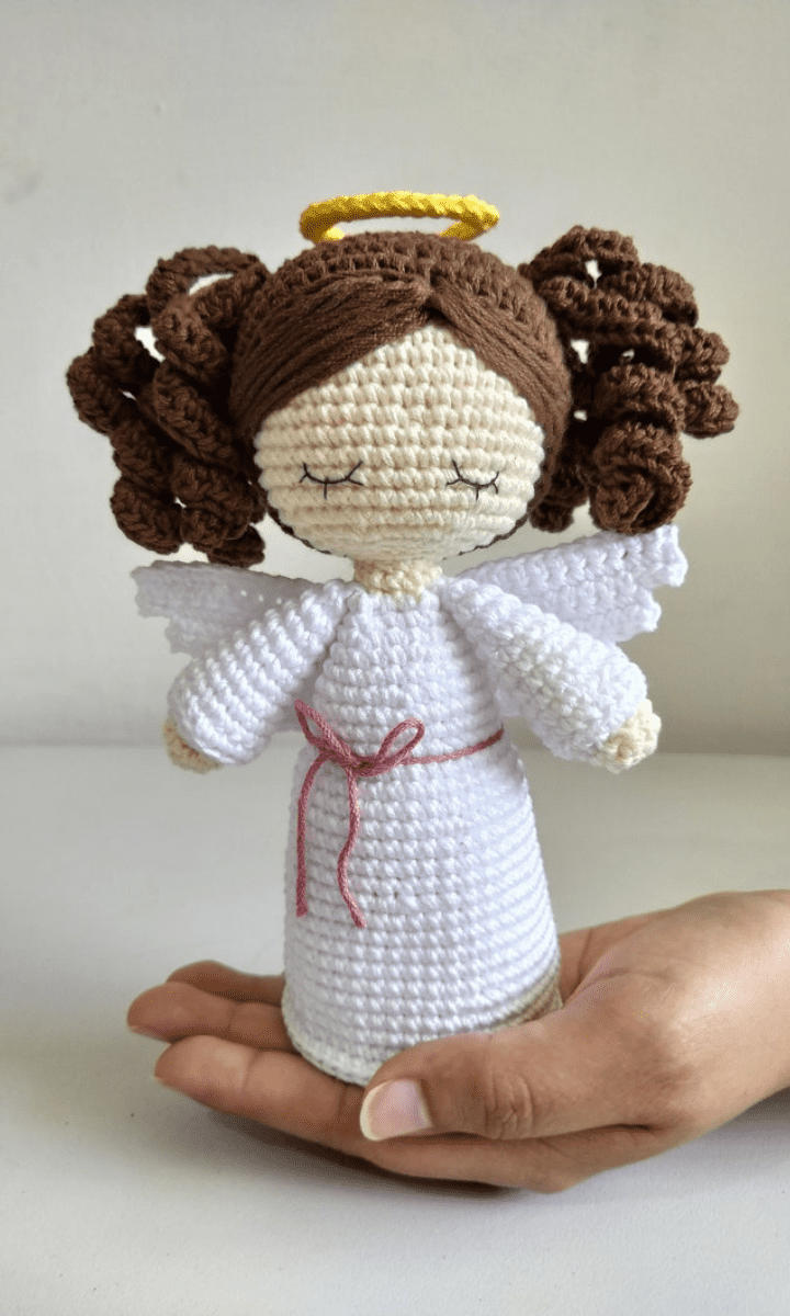 hand holding white crochet angel with brown hair and a halo