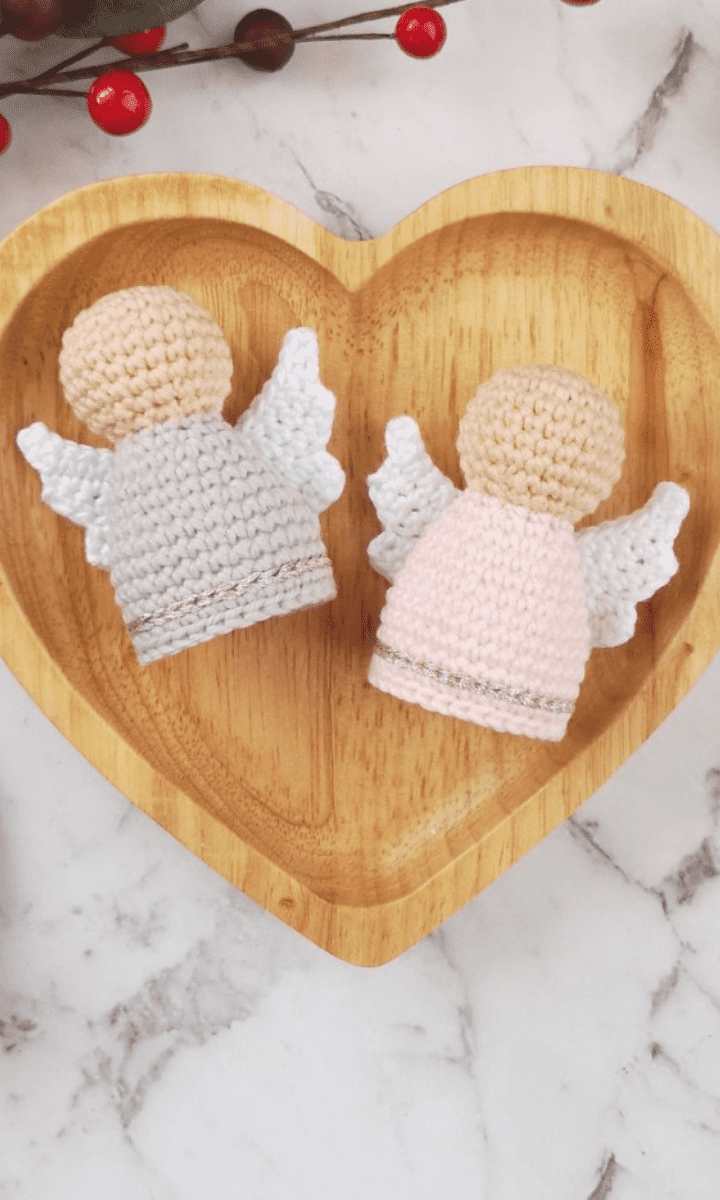 two white crochet angels in wooden heart-shaped bowl