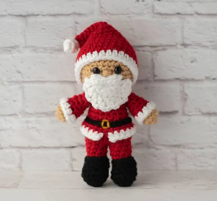 Crochet Santa in red suit, black boots and red and white hat.