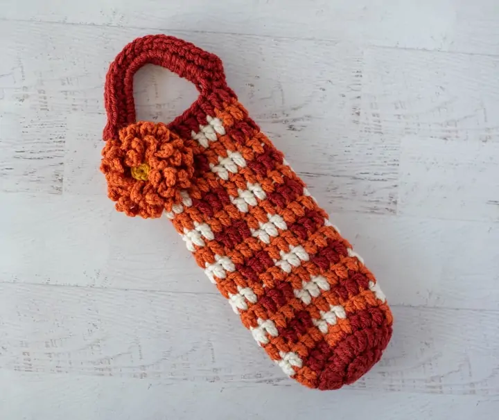 Crochet Orange Plaid Wine Cozy with Orange Flower Laying on table