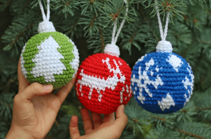 three spherical ornaments: one green with trees, one red with reindeer, and one blue with snowflakes