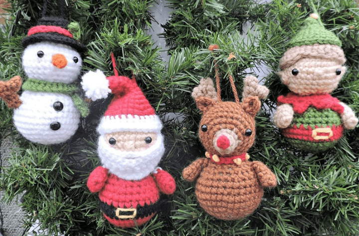 four crochet amigurumi ornaments: one snowman, one santa, one reindeer, and one elf