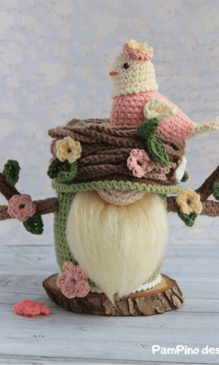 green and pink spring gnome with flowers, branches, a nest, and a bird