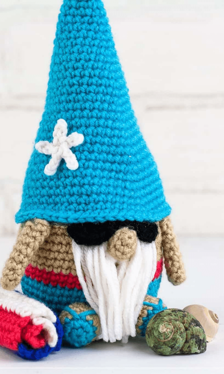 crochet summertime gnome with beach towel, flip flops, sunglasses, and sea shells