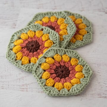 4 crochet sunflower coasters in brown, orange, yellow and green yarn