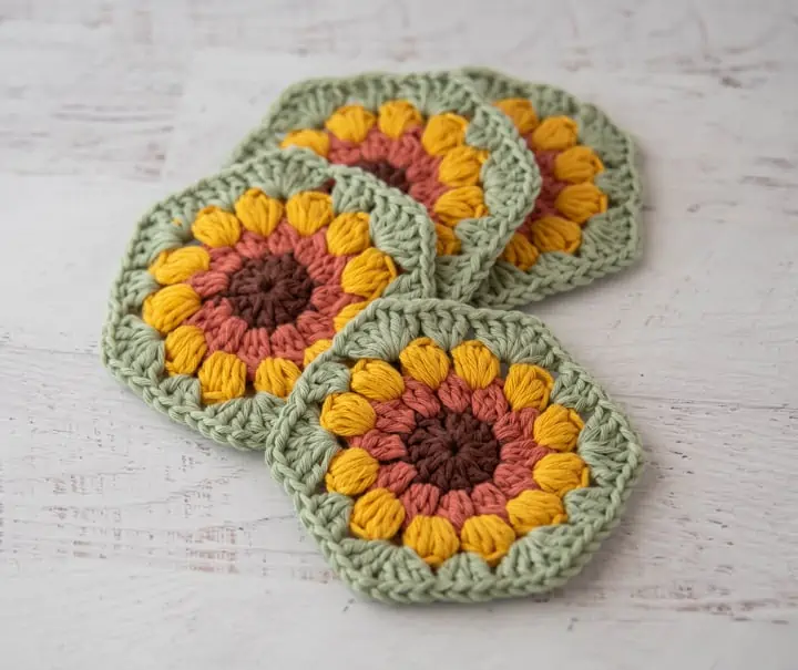 4 crochet sunflower coasters in brown, orange, yellow and green yarn