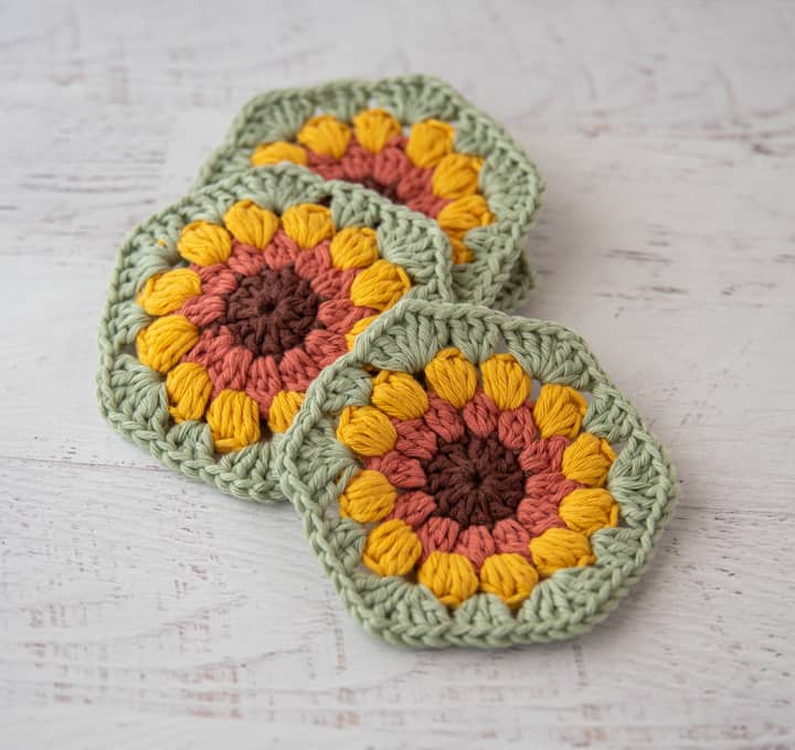 4 crochet sunflower coasters in brown, orange, yellow and green yarn
