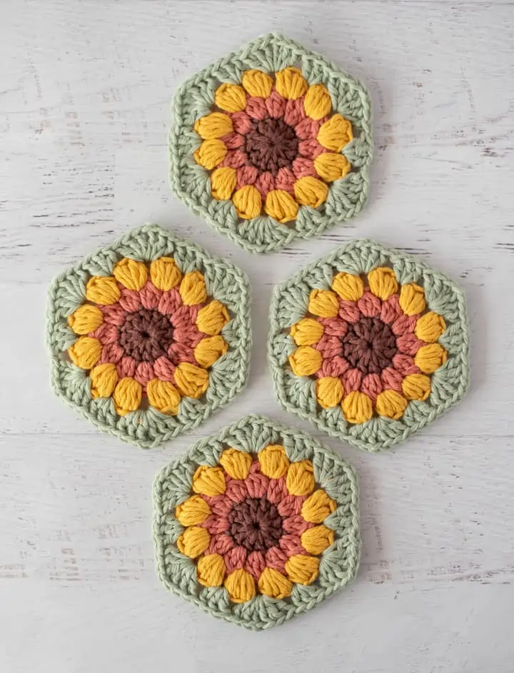 4 crochet sunflower coasters in brown, orange, yellow and green yarn