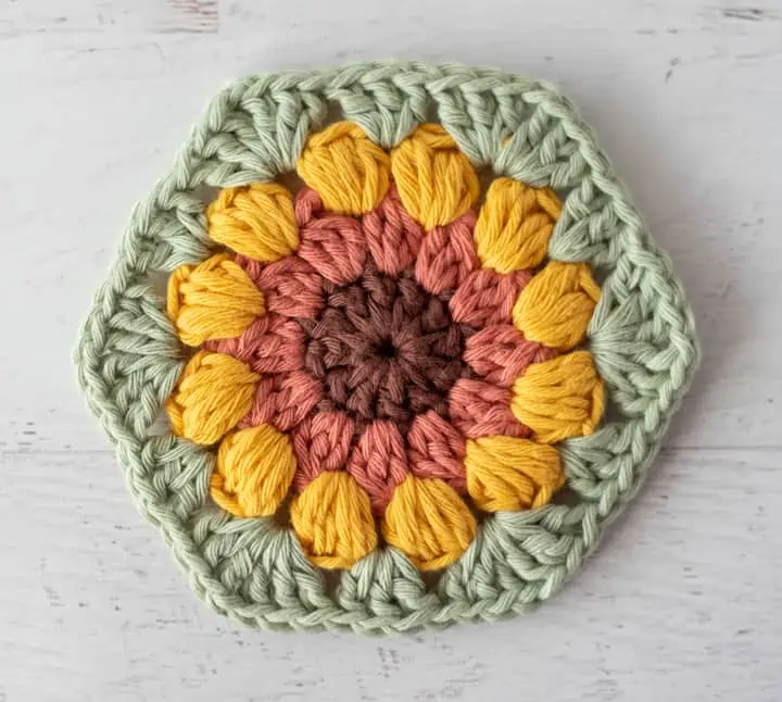 sunflower coaster in brown, orange, yellow and green yarn