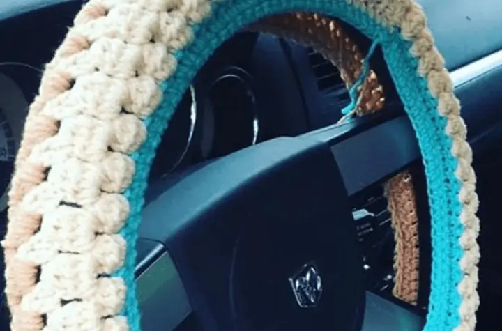 Crochet cotton ball steering wheel cover using white, brown, and blue yarn