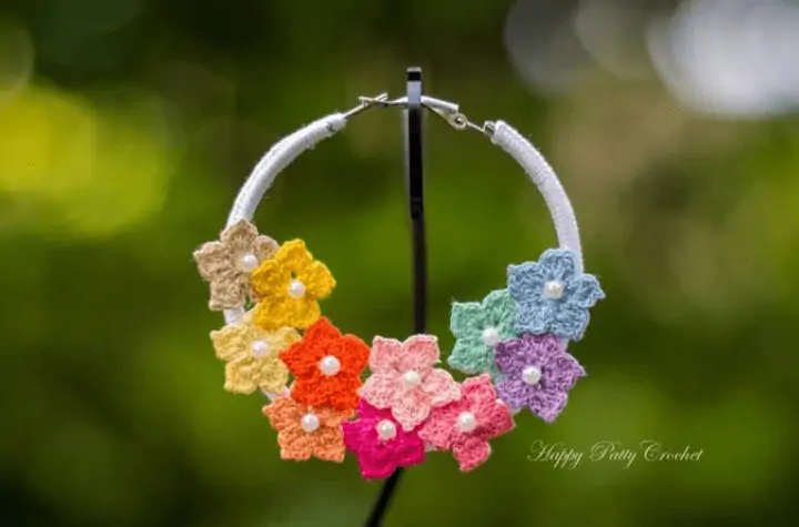 Crochet hoop earring that predominately displays multicolored flowers.