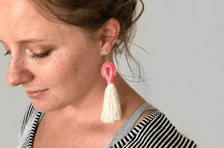 Boucles d'oreilles au crochet avec un pompon blanc en bas.