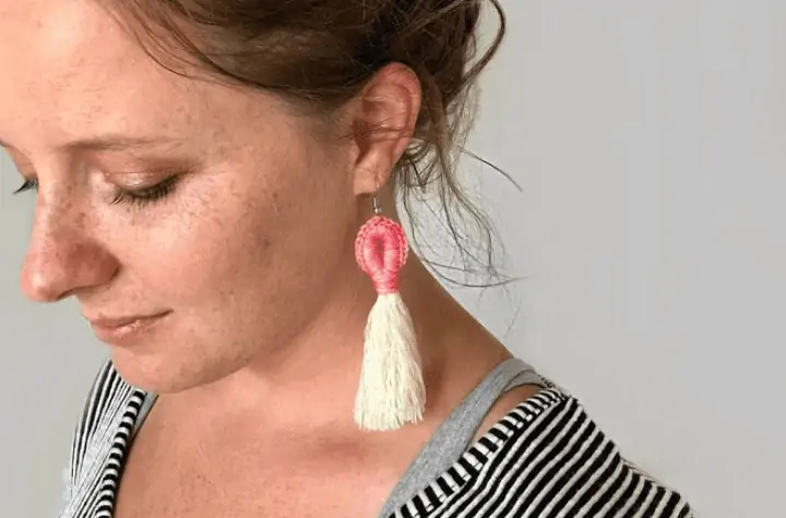 Crochet earrings that feature a white tassel at the bottom.