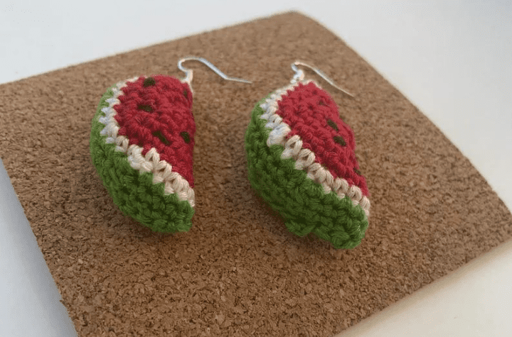 A pair of crochet earrings that look like watermelon slices.