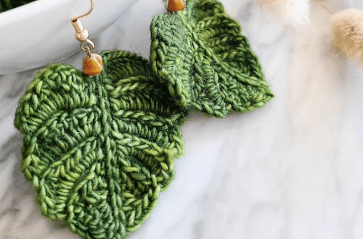 Crochet hook earrings that look like monstera leafs.