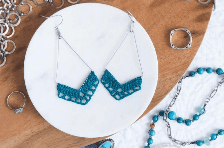 Boucles d'oreilles au crochet qui utilisent du fil de boucle d'oreille pour former un triangle avec des détails au crochet en bas.