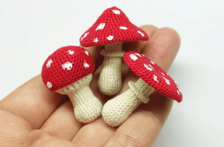 Très petits champignons au crochet dans la paume de la main de quelqu'un