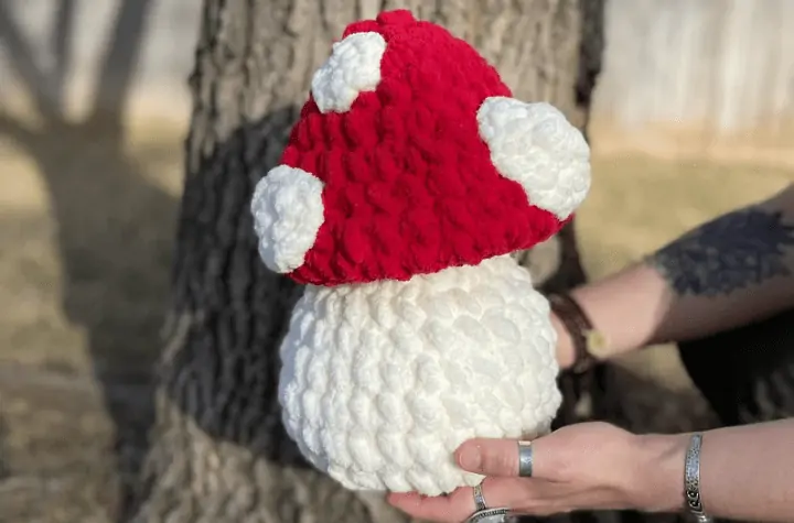 Large stuffed mushroom pillow with red cap and white spots.